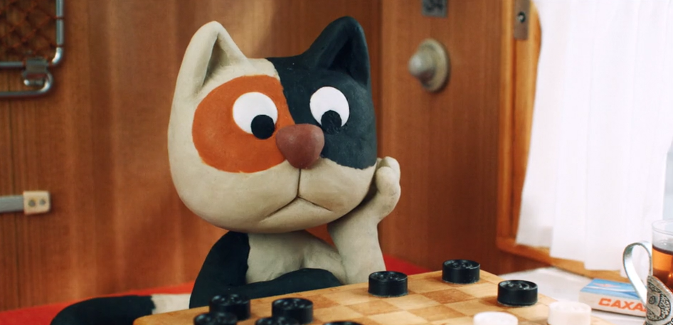 A Claymation ginger, black and white cat sits in front of a draughts bored, head in his paw.