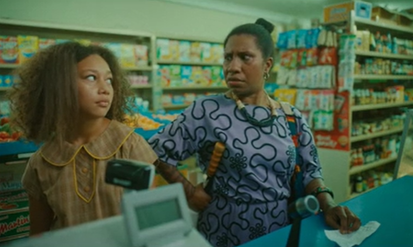 A teenage girl and woman in a shop, standing at a cash register, look at each other in disbelief.