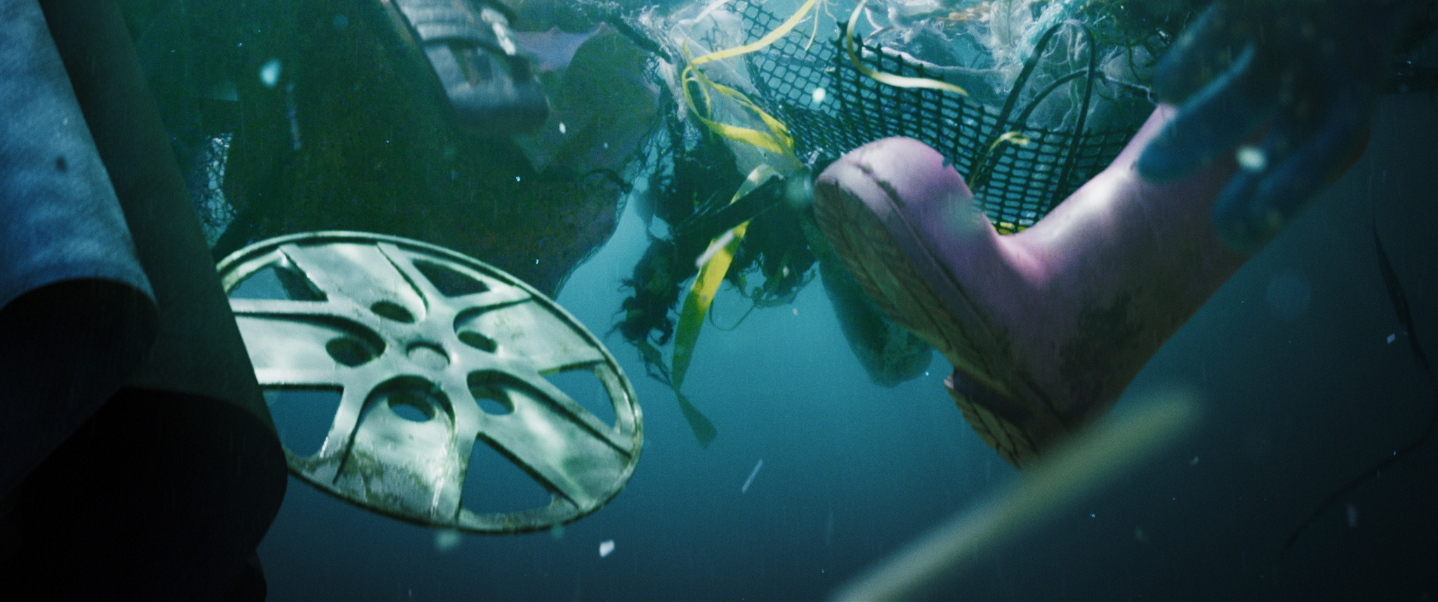 Various pieces of rubbish floating in the ocean, including a hubcap and wellington boot.